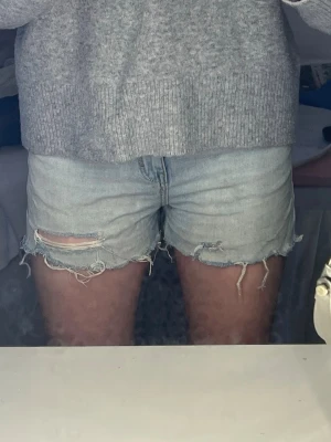 Ljusblå jeansshorts med slitningar - Säljer ett par ljusblå jeansshorts med slitna detaljer. Det är highwaist.