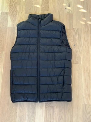 Svart quiltad dunväst - Snygg basic svart väst till våren i storlek M. Inga tecken på användning. 