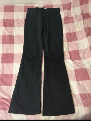 Svarta bootcut Levis - Säljer ett par svarta bootcut jeans från Levi's modell 1052. Jeansen har klassisk femficksdesign, låg midja och utsvängda ben som ger en snygg retrostil. Tillverkade i ett mjukt och slitstarkt bomullsmaterial. 