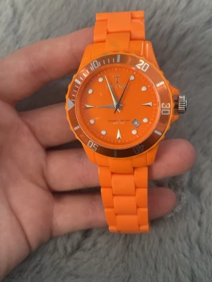 Triwa  - Snygg och färgstark orange klocka med rund urtavla och matchande silikonarmband. Klockan har tydliga vita markeringar och visare samt en vridbar ring runt urtavlan. Perfekt för dig som vill sticka ut med din stil.