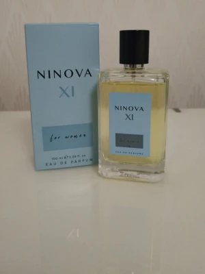 Ninova XI Eau de Parfum 100 ml - Ninova XI Eau de Parfum för kvinnor i en stilren, rektangulär glasflaska med svart kork. Doften kommer i en ljusblå förpackning och flaskan har en matchande etikett. Innehåller 100 ml och har en fräsch, modern look.