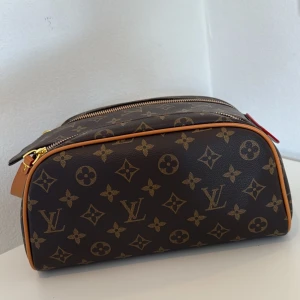 Brun necessär i stor trendig modell, monogram necessär - Säljer en klassisk necessär i brunt monogrammönstrat populärt / trendigt mönster. Den är både praktisk och mycket rymlig. Väskan har två dragkedjor upptill och en rektangulär form, perfekt för att organisera dina hygienartiklar, smink eller småsaker. 
