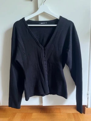 Svart figursydd kofta med knappar och v-ringning - Stilren svart figursydd kofta från Gina Tricot med v-ringning och dekorativa knappar framtill. Långärmad modell i mjukt stickat material som passar perfekt till lager på lager. Enkel att matcha med olika outfits. Välj gärna instabox💐