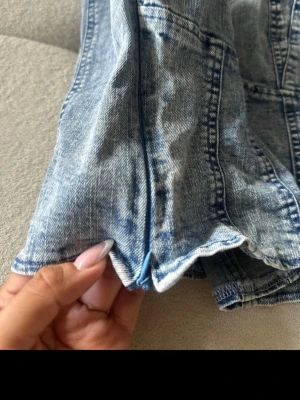 Blå denim bustier crop top - Snygg blå denim bustier crop top med breda axelband och markerade sömmar för en cool look. Toppen har dragkedja i sidan och är tillverkad i ett klassiskt jeansmaterial. Perfekt att styla med höga jeans eller kjol för en trendig outfit.