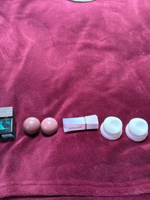 Skönhetspaket med smink och sporttejp - Ett blandat paket med skönhetsprodukter: parfymflaska, två rosa runda sminkprodukter, SHEGLAM-läppstift i rosa hylsa, två vita burkar samt ett 2-pack Assist coach sporttejp i vitt. Perfekt för dig som gillar att testa olika skönhetsprodukter.