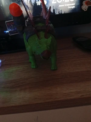 Grön dinosaurieleksak med raket - Cool grön dinosaurieleksak i plast med röda taggar på ryggen och en stor grå raket på sidan. Perfekt för dig som gillar dinosaurier och actionleksaker. Leksaken har detaljer som gör den extra rolig att leka med. Även ha som dekoration.
