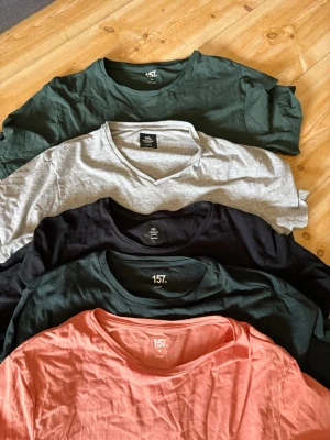 Fem basic t-shirts i olika färger - Säljer ett paket med fem basic t-shirts i färgerna grön, grå, svart, mörkgrön och korall. Alla har rund halsringning förutom den grå som har v-ringning. Perfekta till vardags och gjorda i mjuk bomull för skön känsla.