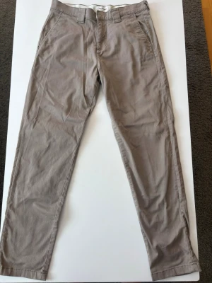 Beige chinos från Jack & Jones  - Snygga beige chinos från Jack & Jones med klassisk rak passform och diskreta sidofickor. Tillverkade i mjukt bomullstyg för en bekväm känsla. Perfekta för en avslappnad men stilren look. 