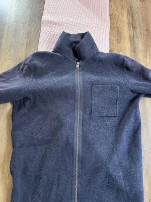 Mörkblå ziptröja Selected HOMME - Snygg mörkblå ziptröja med hög krage och en bröstficka. Tröjan har hel dragkedja framtill och är tillverkad i ett mjukt, lite tjockare material som passar perfekt när det är kyligt. Enkel och stilren design som funkar till det mesta. 