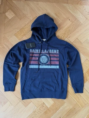 Saint Laurent hoodie - Mörkblå Saint Laurent hoodie med luva, den är äkta och säljer på grund av att den är för liten. Kom gärna med bud så kan vi lösa något snabbt