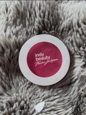 Indy Beauty Make Me Blush Rouge - Endast testad Säljer ett Indy Beauty Make Me Blush rouge i nyansen Inez. Rouget kommer i en rund, vit dosa med rosa etikett och är 100% veganskt. Perfekt för att ge kinderna en fräsch, rosig ton. Innehåller 9,5 g produkt.