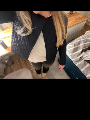 Mörkblå quiltad jacka - Snygg mörkblå quiltad jacka med lång ärm och öppen framtill. Jackan har en stilren, minimalistisk look och passar perfekt till både jeans och kjol. Materialet känns lätt och bekvämt, och den quiltade strukturen ger en trendig touch.