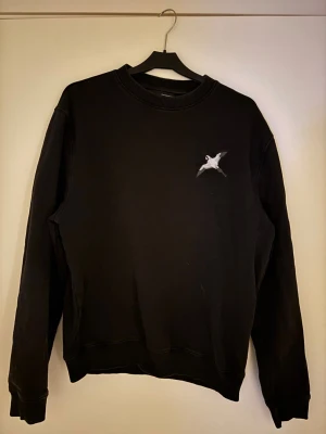 Svart sweatshirt från Arigato - Svart sweatshirt från Axel Arigato med rund hals och ett litet vitt fågeltryck på bröstet. Tröjan har ribbade muddar vid ärmslut och nederkant. Perfekt för en avslappnad och stilren look. Mycket bra skick. Nypris 1200kr. 