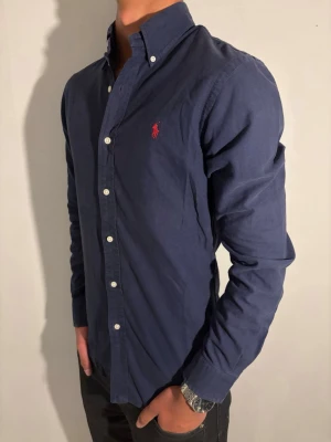 Mörkblå skjorta från Ralph Lauren - strl S - Ralph Lauren skjorta 👔✨ Mörkblå och stilren 💙 Storlek S 👀 I fint skick och väl omhändertagen 🔥 Nypris runt 1 400 kr 💸 – vårt pris 399 kr 🔥 Snygg passform som funkar både uppklätt och mer avslappnat 😎 Klassisk och tidlös design Modellen på bild är ca 182 cm och väger runt 65 kg Kolla in profilen för flera skjortor 👀✨ Hör av er om ni har frågor eller vill ha fler bilder 💬