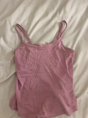 Rosa ribbad linnetopp från Cotton On - Säljer en ljusrosa ribbad linnetopp från Cotton On med smala axelband. Toppen är figurnära och har en enkel, stilren design som passar perfekt till sommaren. !!Om du köper välj gärna att hämta vid upphämtningsställe då det blir enklare för mig att posta på det viset!!