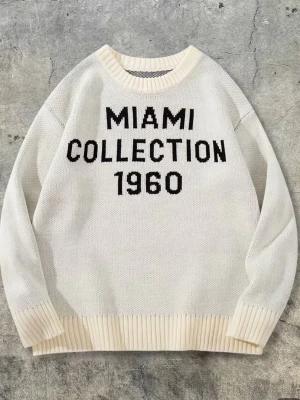 Miami collection - Vit stickad tröja med svart text 'MIAMI COLLECTION 1960' på framsidan. Tröjan har rund halsringning och ribbade muddar vid ärmslut och nederkant. Materialet är grovt stickat och ger en avslappnad look.
