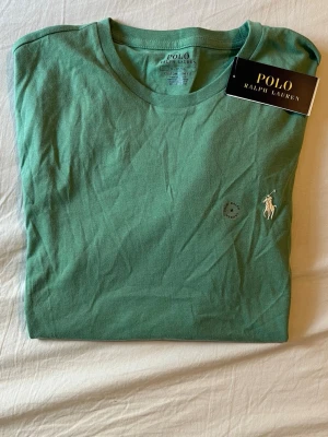 Grön t-shirt från Polo Ralph Lauren - Snygg grön t-shirt från Polo Ralph Lauren i storlek M slim fit och ikoniska broderade loggan på bröstet. Tillverkad i mjuk bomull som känns skön mot huden. Tröjan är helt ny med lappen. Nypris: 1100kr, Mitt pris: 499kr / Skriv vid minsta lilla funderingar 🤗