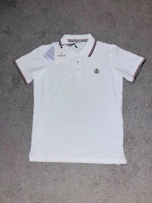 Vit Moncler Piké - ❗ DIGITALT KVITTO FINNS❗  📊 Färg: Vitt 📝 Storlek: Medium(M)  📏 Mott: Axel till axel 48 Cm--Midja till hals 64 Cm  ♻️ Använd fåtal gånger-Nytt skick  📦 Postar inom 24h  Hör av er vid funderingar eller prisförslag