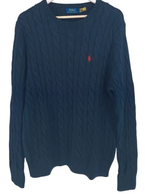 Polo Ralph lauren tröja - Marinblå stickad cable knit tröja i från Ralph lauren i storlek L som är i mycket bra skick, tags finns kvar och det finns även en qr kod i tröjan gör att kolla äktighet. Nypris 2350kr mitt pris endast 999kr. Hör gärna av er vid frågor. Mvh Viktor🙌😊