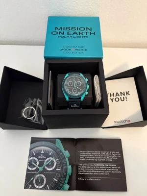 Omega x Swatch Mission on Earth klocka - Snygg Omega x Swatch Mission on Earth Polar Lights klocka i turkos och svart. Klockan har biokeramisk boett, svart urtavla med vita detaljer och kronograf-funktion💫