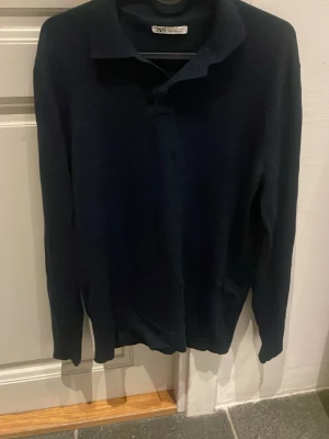 Mörkblå långärmad piké från Zara - Snygg mörkblå långärmad tröja från Zara Man med klassisk krage och enkel design. Perfekt för en stilren look. Tröjan är tillverkad i ett mjukt och tunt material som känns skönt mot huden.