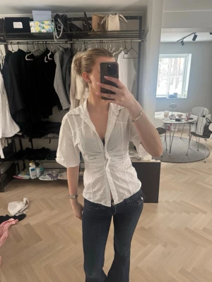 Vit kortärmad skjorta med knappar - Säljer en vit skjorta med korta ärmar och v-ringning. Lappen är borta men skulle gissa på att storleken är 34/36