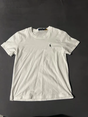 Vit t-shirt från Polo Ralph Lauren - Klassisk vit t-shirt från Polo Ralph Lauren med rund halsringning och den ikoniska broderade loggan på bröstet. Tillverkad i mjuk bomull och har en normal passform. Perfekt basplagg för alla tillfällen.