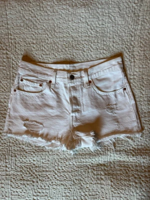 Vita Levi’s jeansshorts med fransig kant - Snygga vita Levi’s jeansshorts med fransig kant och slitna detaljer framtill. 