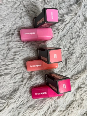 Huda Beauty läppstift i tre färger - Tre läppstift från Huda Beauty i snygga färger: ljusrosa, korall och stark rosa. Hylsorna är fyrkantiga och gjorda i plast med matchande färg på locket. Perfekt för dig som gillar färgstarka och trendiga läppar.