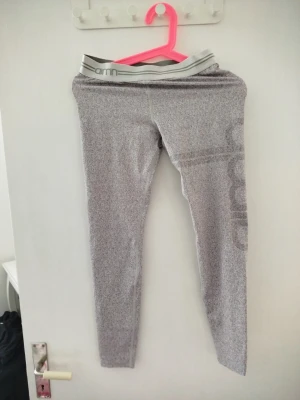 Grå träningstights från Aim'n - Snygga grå träningstights från Aim'n med resår i midjan och diskret logga längs benet. Tillverkade i stretchigt material av 73% polyester och 27% spandex, perfekta för gymmet eller löprundan.