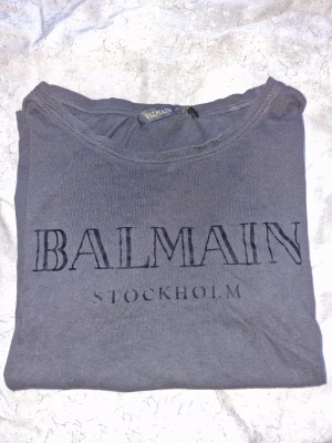 Balmain x H&M svart t-shirt - T-shirt från Balmain x H&M-kollektionen. Tröjan är svart/mörkgrå med texten "BALMAIN STOCKHOLM" tryckt på framsidan i svart sammet 🖤