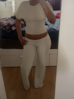 zara sett - S tröjan M byxorna. Säljer en stilren vit croppad topp med korta ärmar och rund hals. Materialet känns mjukt och stretchigt, vilket gör den bekväm att bära hela dagen. den har en liten fläck vid ena foten men inte så synligt 