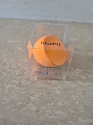 Beautyblender - En mjuk och flexibel orange beautyblender från Blushy. Perfekt för att blanda foundation, concealer eller puder. Svampen har en droppformad design som gör det enkelt att komma åt både större och mindre områden i ansiktet. Levereras i genomskinlig förpackning.