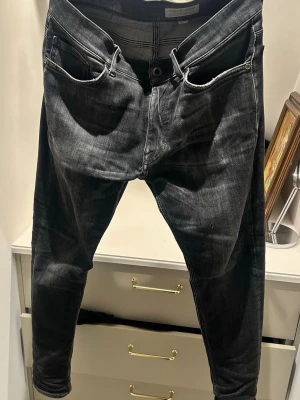Svarta slim fit jeans från Tiger of Sweden  - Säljer ett par svarta slim fit jeans från Tiger of Sweden. Jeansen har fem fickor, smal passform och klassisk knappgylf. Materialet är stretchigt denim som ger en bekväm känsla och snygg siluett. Perfekta för en modern och stilren look. Köpta från nk för 1650kr. Mitt pris 300. Hör av er vid frågor eller funderingar, kan gå ner i pris vid snabb affär 😁