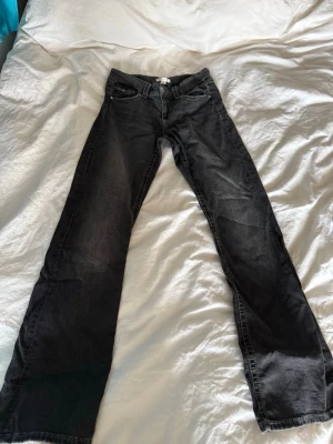 Svarta bootcut jeans - Säljer ett par svarta bootcut jeans med klassisk femficksdesign och knappgylf. Jeansen har en lätt tvättad look och raka ben som går ut något nedtill. Storlek 170. Pris kan diskuteras!