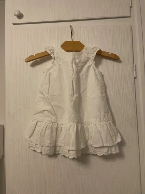 Vit volangklänning  - Söt vit klänning från H&M med volangkant nedtill och diskret broderat mönster. Klänningen är ärmlös och har en rund halsringning, perfekt för varma dagar. Går inte att köpa längre då den är från när jag var liten, alltså 18 år sedan. 