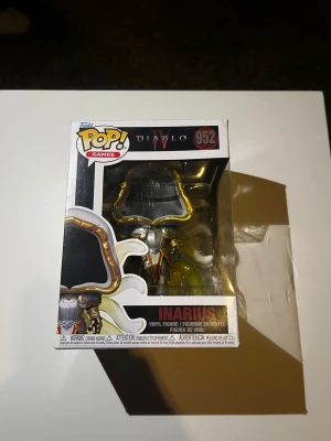 Funko Pop! Games Diablo IV Inarius - Säljer en Funko Pop! Games vinylfigur av Inarius från Diablo IV, nummer 952. Figuren är detaljerad med guldfärgade horn, silverrustning och vita vingar. Kommer i originalförpackning med fönster, perfekt för samlare av gaming-merch eller Diablo-fans.