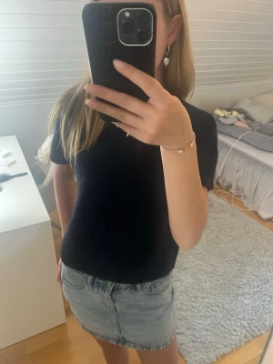 Marinblå stickad topp - En enkel och stilren stickad marinblå topp med korta ärmar och rund hals. Passformen är normal och materialet ser ut att vara mjukt och bekvämt, perfekt till jeans eller kjol.