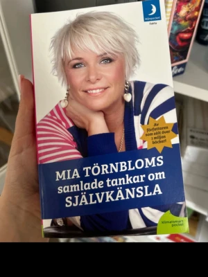 Samlade tankar om självkänsla - En pocketbok av Mia Törnblom med titeln 'Samlade tankar om självkänsla'. Omslaget har en färgstark design med blå, rosa och vita toner samt ett foto på författaren. Boken är utgiven av Månpocket och handlar om självkänsla och personlig utveckling.