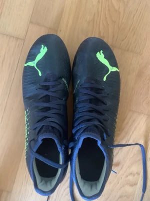Svarta Puma fotbollsskor med neon - Säljer ett par mörkblåa puma fotbollsskor. De är använda försiktigt och har inga hål.  Vid frågor eller mer bilder är de bara o höra av sig. Jag svarar nästan direkt. PRIS KAN DISKUTERAS!