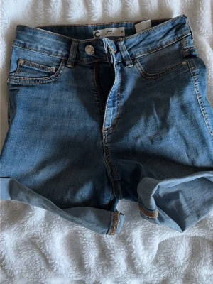Blå denimshorts med uppvik - Snygga blå denimshorts med en längre modell. Perfekta för varma dagar och enkla att matcha med olika toppar.