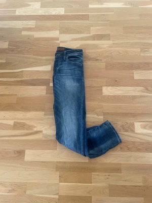 Blå jeans från Jack & Jones - Snygga blå jeans från Jack & Jones med klassisk femficksdesign och diskreta slitningar framtill. Jeansen har en rak passform och är tillverkade i denim med en lätt tvättad look. Perfekta för en avslappnad och trendig stil.