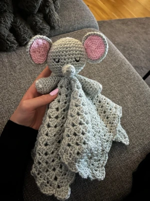 Virkad snuttefilt elefant - Supergullig handvirkad snuttefilt i form av en elefant med stora grå öron och rosa insida. Huvudet och armarna är stoppade och filten är mjuk och luftig. Perfekt som present till små barn eller som mysig kompis.