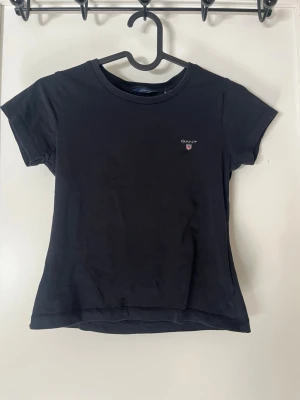 Svart t-shirt från Gant - En stilren svart t-shirt från Gant med liten logga på bröstet. Klassisk rund halsringning och korta ärmar. 