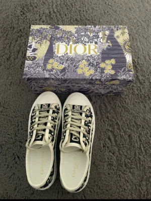 Dior Oblique låga sneakers - Snygga Dior Oblique sneakers i lågt snitt med vit sula och marinblått/vitt monogrammönster. Skorna har vita snören och detaljer med Christian Dior-logga på sidan och plösen. Tillverkade i canvas och gummi för en clean och trendig look.