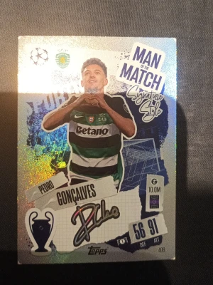Man of the Match fotbollskort Topps - Glittrigt samlarkort från Topps med fotbollstema, föreställande en spelare i grönvit randig tröja. Kortet har texten 'Man of the Match', spelarens namn och en tryckt autograf. Perfekt för dig som gillar fotboll och samlarkort.