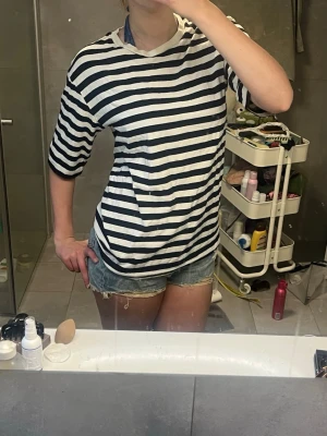Randig t-shirt i marin stil - Säljer en classy randig t-shirt med svarta och vita ränder. T-shirten har korta ärmar, rund halsringning och en loose passform. Perfekt för en avslappnad och stilren look. Med styling kan den såklart passa till somriga utegångar. Bra kvalité från COS