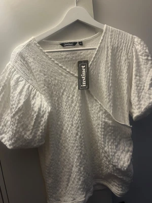 Vit topp - En supersöt liten topp med puff ärmar köpt på kids brand store men från märket Instinct, storlek 170 och helt oanvänd (lapp finns kvar). Bara att höra av er om mer bilder önskas💕