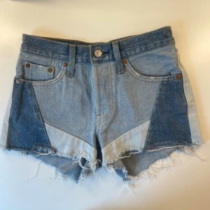 Levi's jeansshorts  - Snygga jeansshorts från Levi's i olika blå nyanser med patchwork-design och råa, fransiga kanter. Klassisk femficksmodell. Perfekta för sommaren och ger en cool, avslappnad vibe. Passar både s och xs