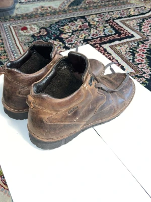 Bruna läderkängor från Gallus - Snygga bruna kängor från Gallus i äkta läder med robust sula och klassisk snörning. Perfekta för dig som gillar en tidlös och avslappnad stil. Märkeslogga på sidan och plös, samt detaljerade sömmar för extra karaktär.